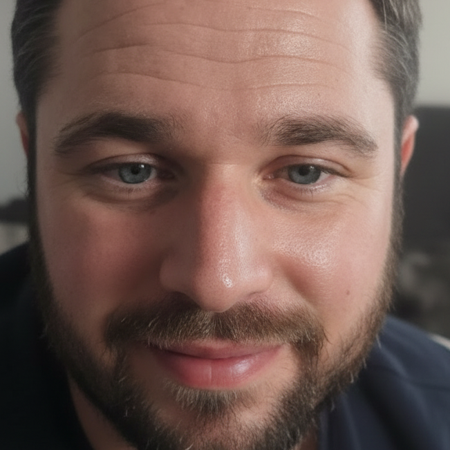Close-up portrait of a smiling man with a beard and blue eyes.